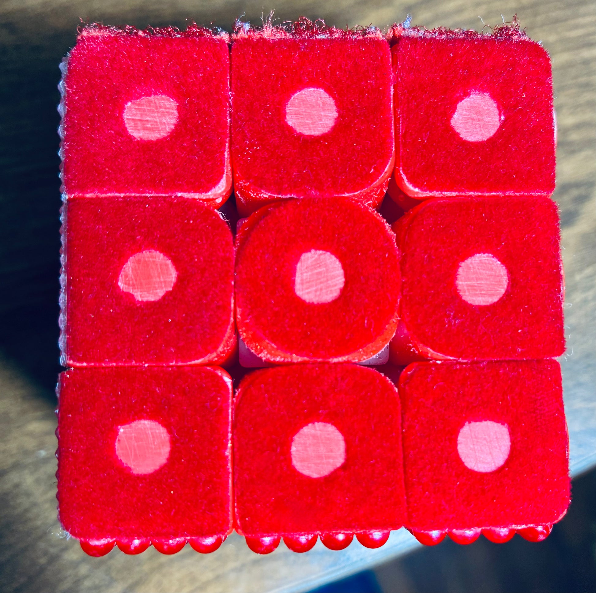 Close up of Rubik's cube side with soft red velvet with circular holes in the center of each square